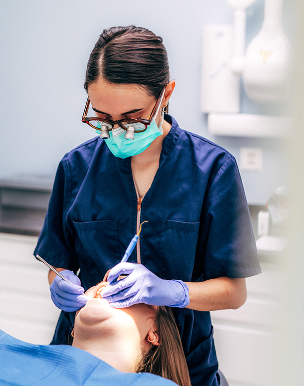 A dentist removes tartar from a patient's teeth